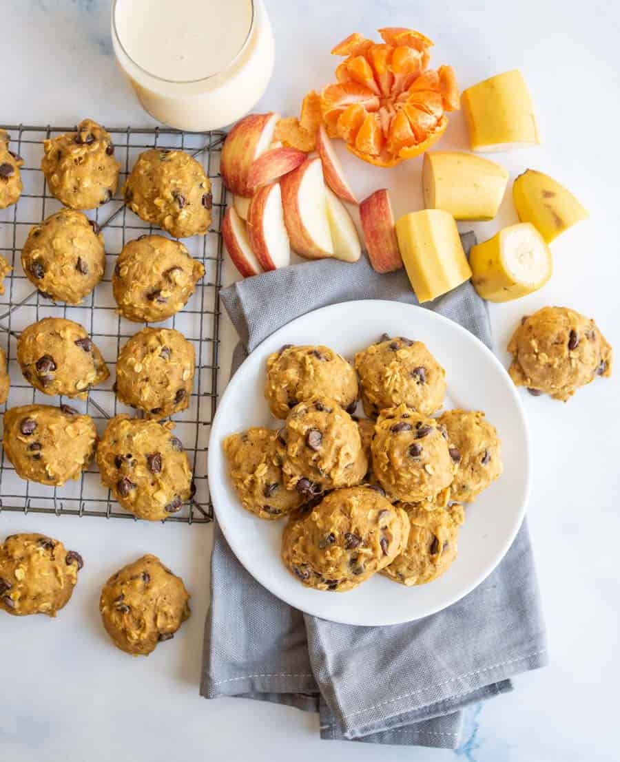 plate of breakfast cookies with some on a cooling rack with milk and fresh fruit all around