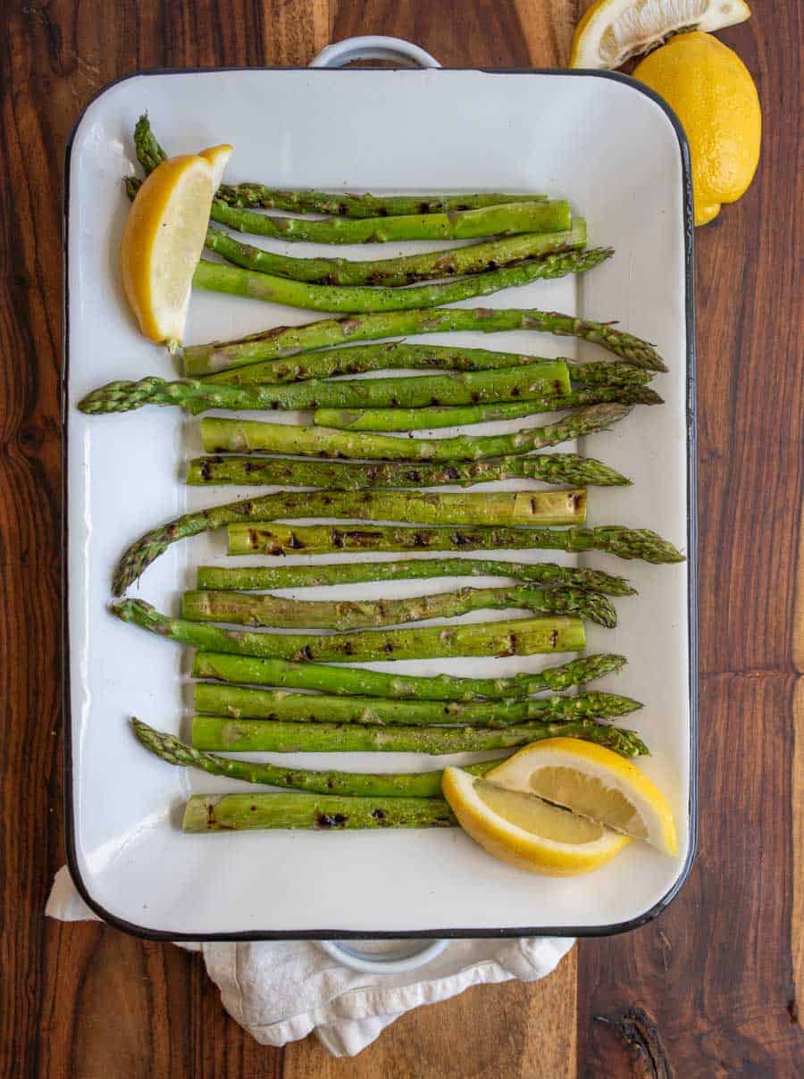 top view of cooked asparagus and fresh lemon on a white baking tray