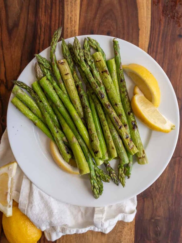 cooked asparagus and fresh lemon on a white plate