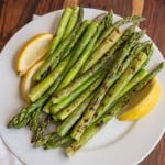 cooked asparagus and fresh lemon on a white plate