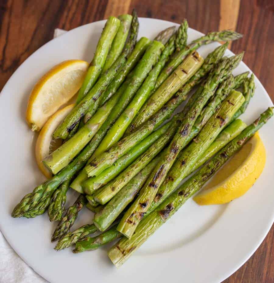 cooked asparagus and fresh lemon on a white plate