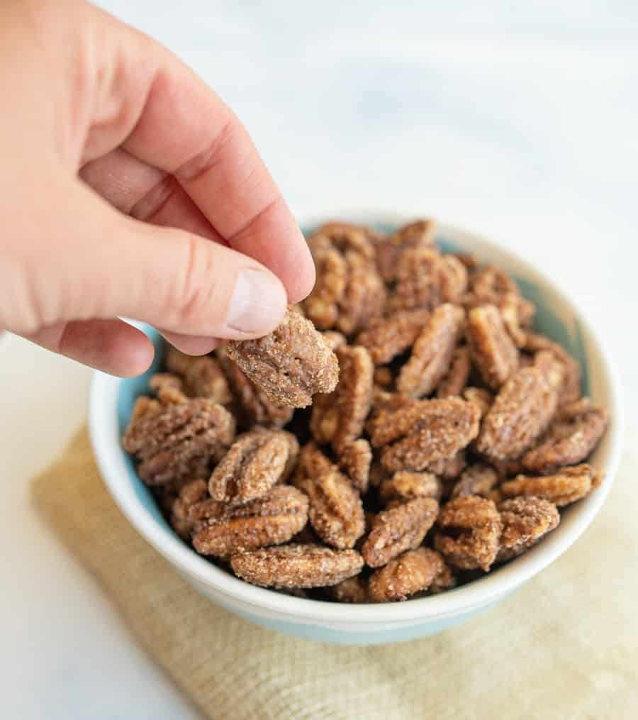 POV hand picking out a candied pecan from a bowl