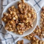 top view of a white bowl with shards of homemade peanut brittle