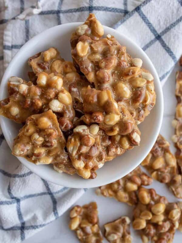 top view of a white bowl with shards of homemade peanut brittle