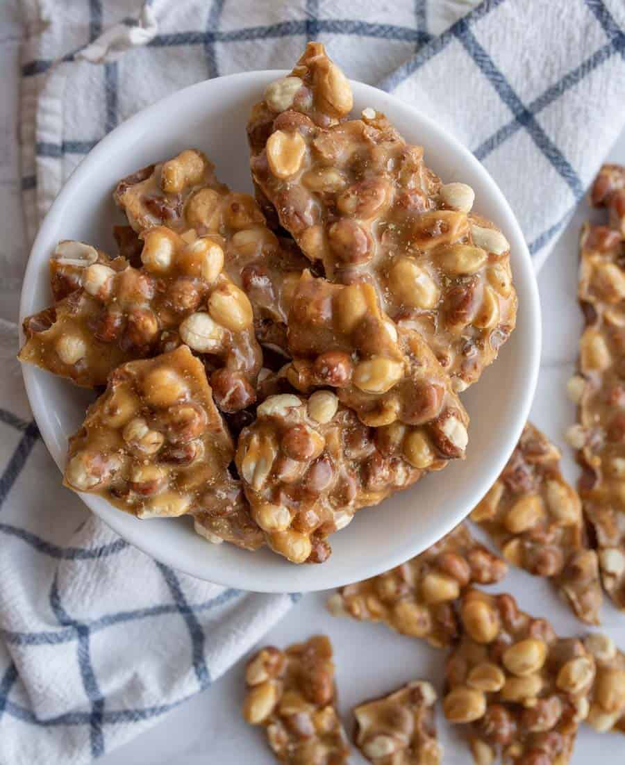 top view of a white bowl with shards of homemade peanut brittle