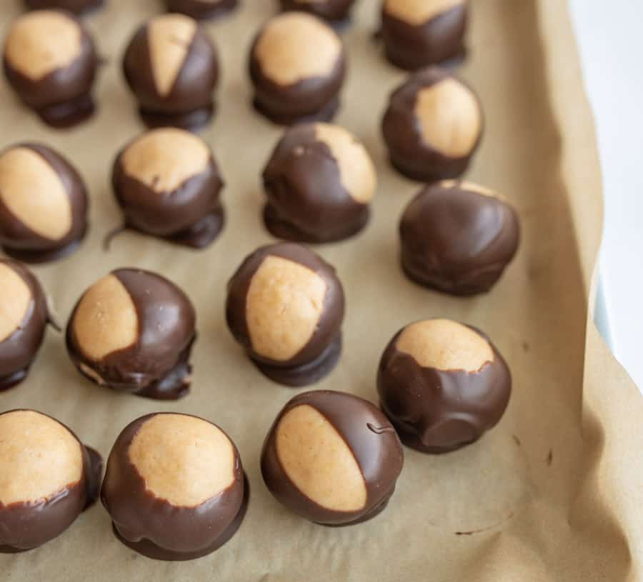 round truffle like chocolates on parchment paper with what looks like a lighter color to the shell of each.