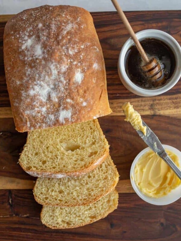 top view of a loaf of sliced airy potato bread with honey and butter in the background