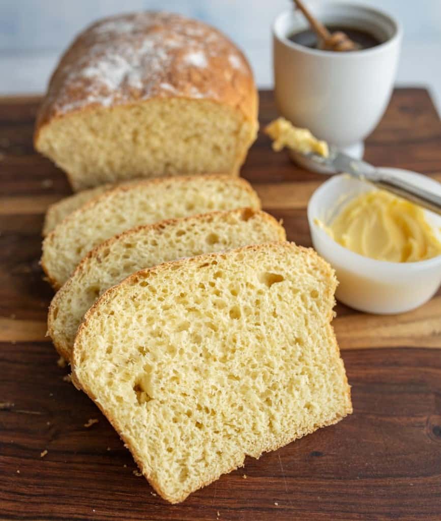 sliced airy potato bread with honey and butter in the background