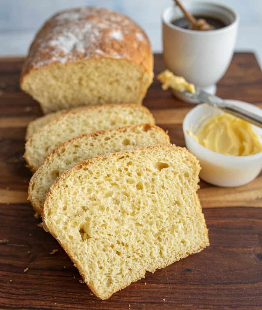 sliced airy potato bread with honey and butter in the background.