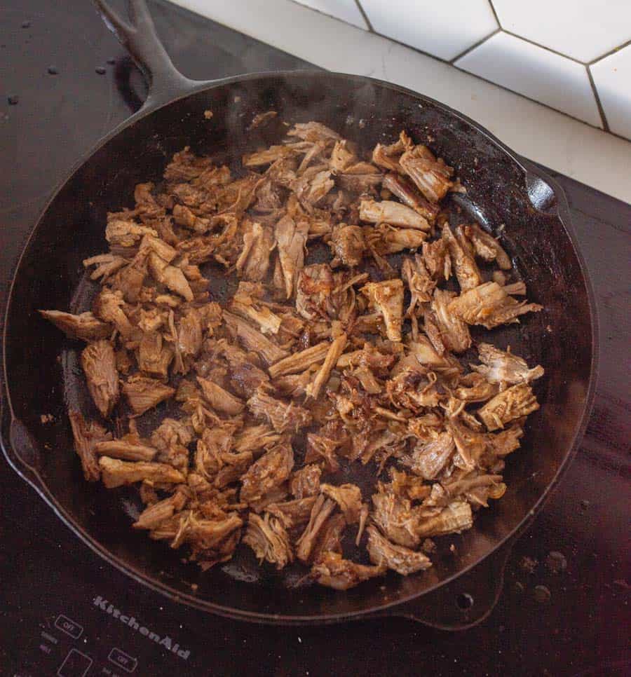 cast iron pot cooking off and browning shredded pork for Carnitas recipe