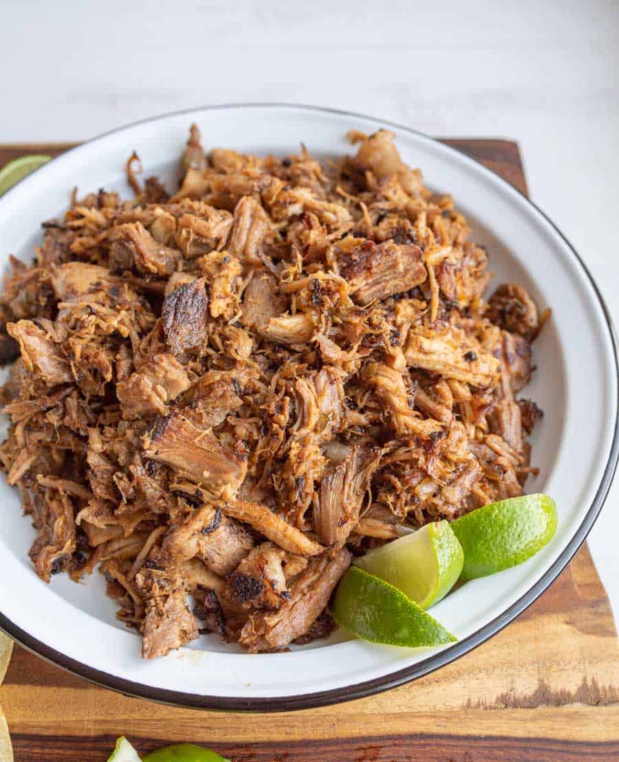 photo of shredded pork on a white plate with fresh lime