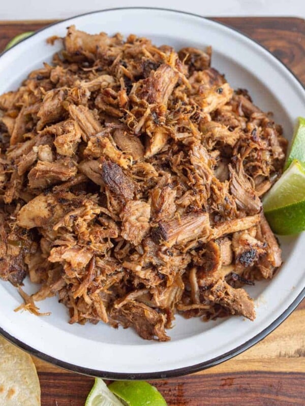 top view of shredded pork on a white plate with fresh lime