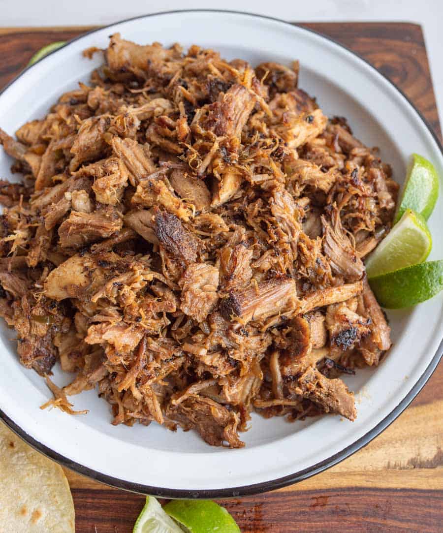 top view of shredded pork on a white plate with fresh lime