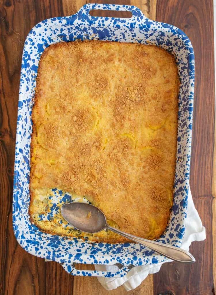 photo of a blue spotted baking dish with crumbly topped yellow squash casserole with one piece missing