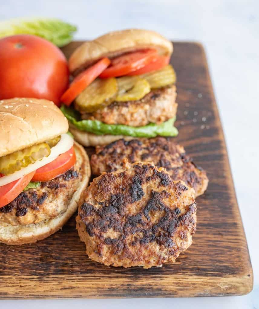 turkey burgers on a cutting board some without a bun and others assembled with all the fixings