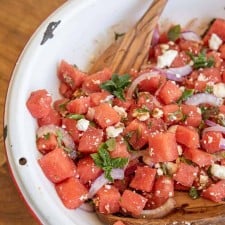 close up photo of the watermelon feta salad with wooden spoons