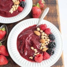 two white bowls with acia bowl recipe with fresh fruit, nuts, and granola