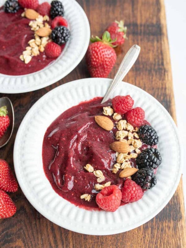 two white bowls with acia bowl recipe with fresh fruit, nuts, and granola