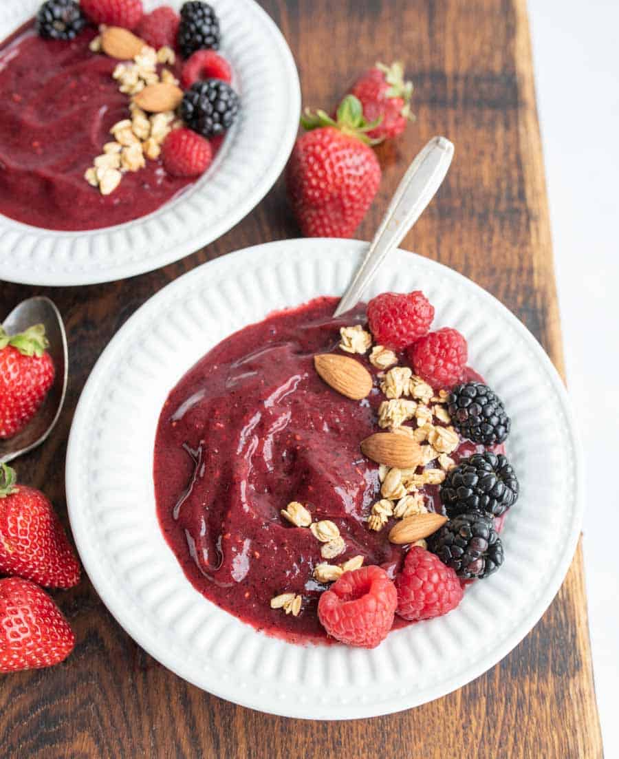 two white bowls with acia bowl recipe with fresh fruit, nuts, and granola