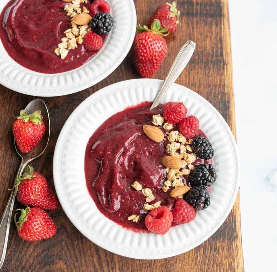 two white bowls with acia bowl recipe with fresh fruit, nuts, and granola