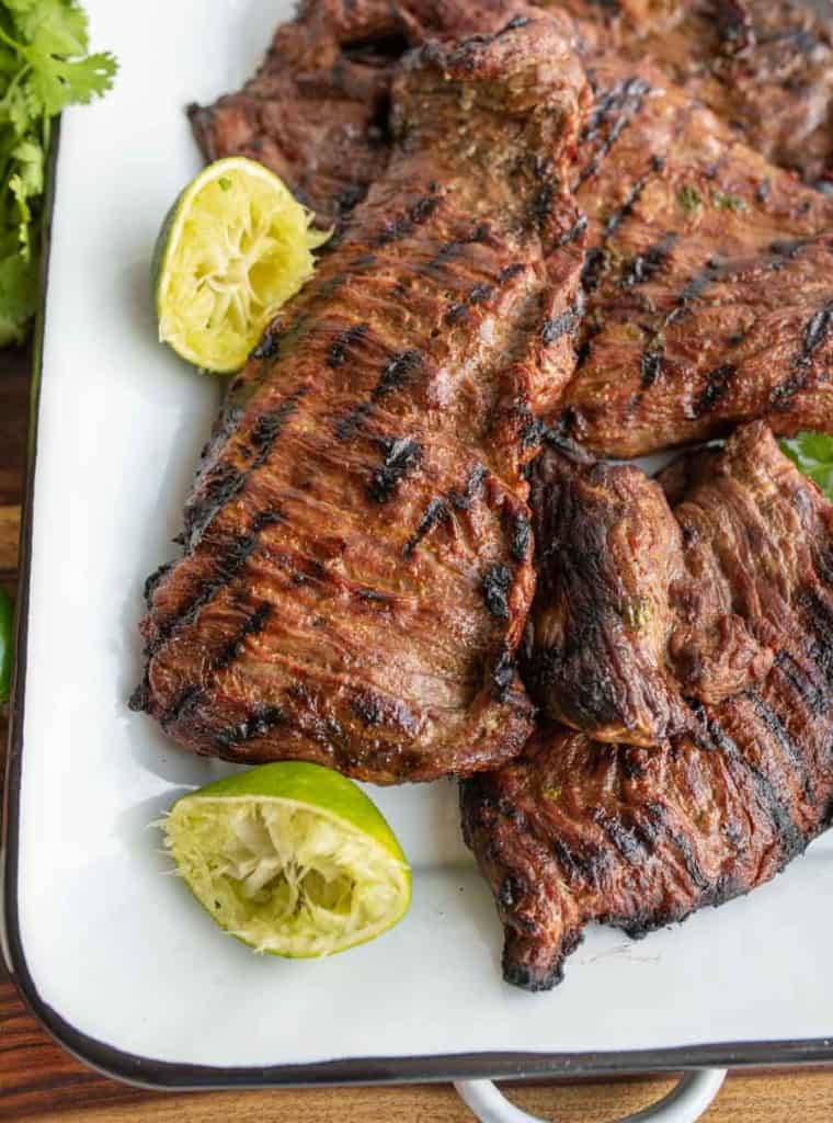 corner of the dish with carne asada steak and squeezed limes