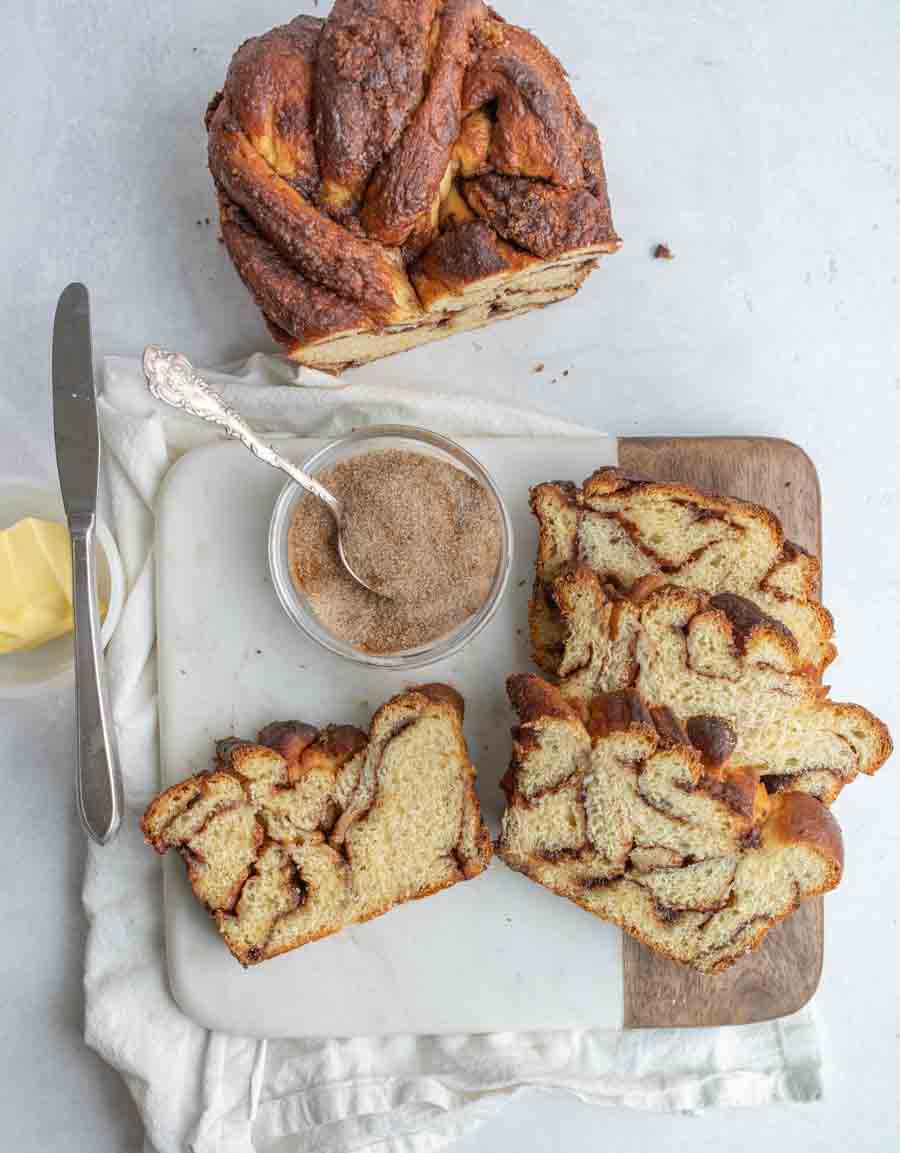 top view of cinnamon baked bread, the loaf is sliced with cinnamon sugar and butter on the board