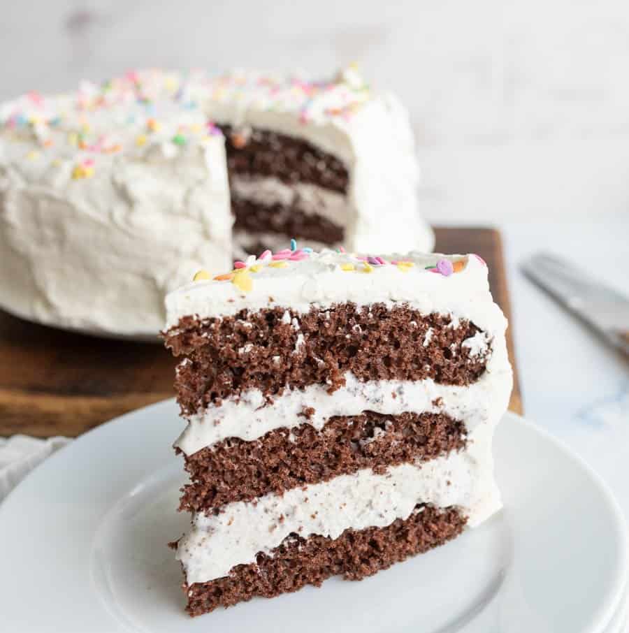 close up of a slice of ice cream cake with the whole cake in the background