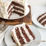 3/4 of an ice cream cake, chocolate cake and white frosting looking into the center with the slices on white plates in front