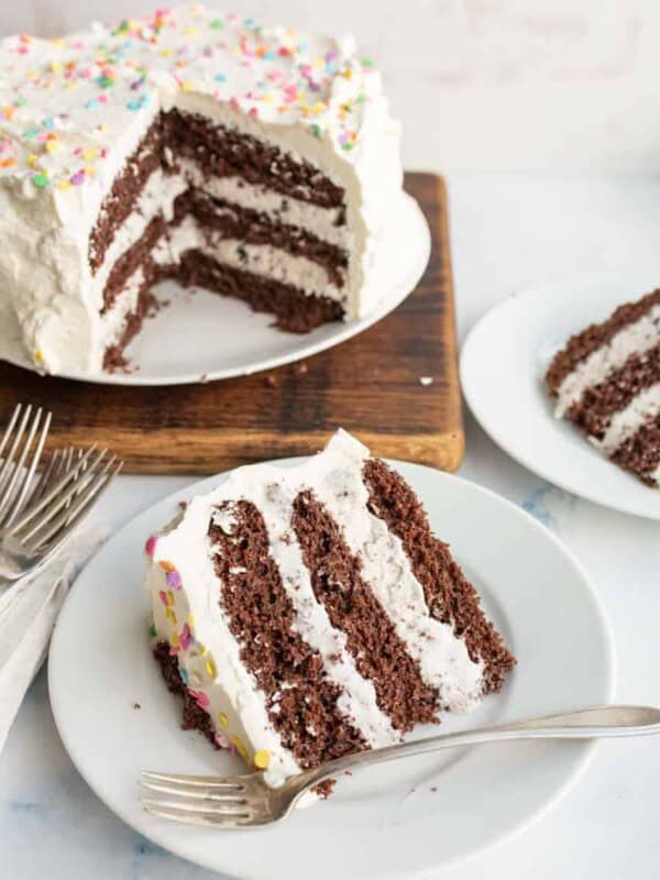 3/4 of an ice cream cake, chocolate cake and white frosting looking into the center with the slices on white plates in front