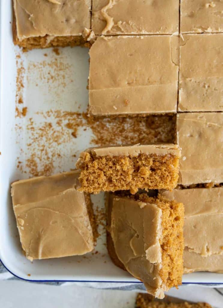 slices of pumpkin cake in a sheet pan with a caramel icing on top