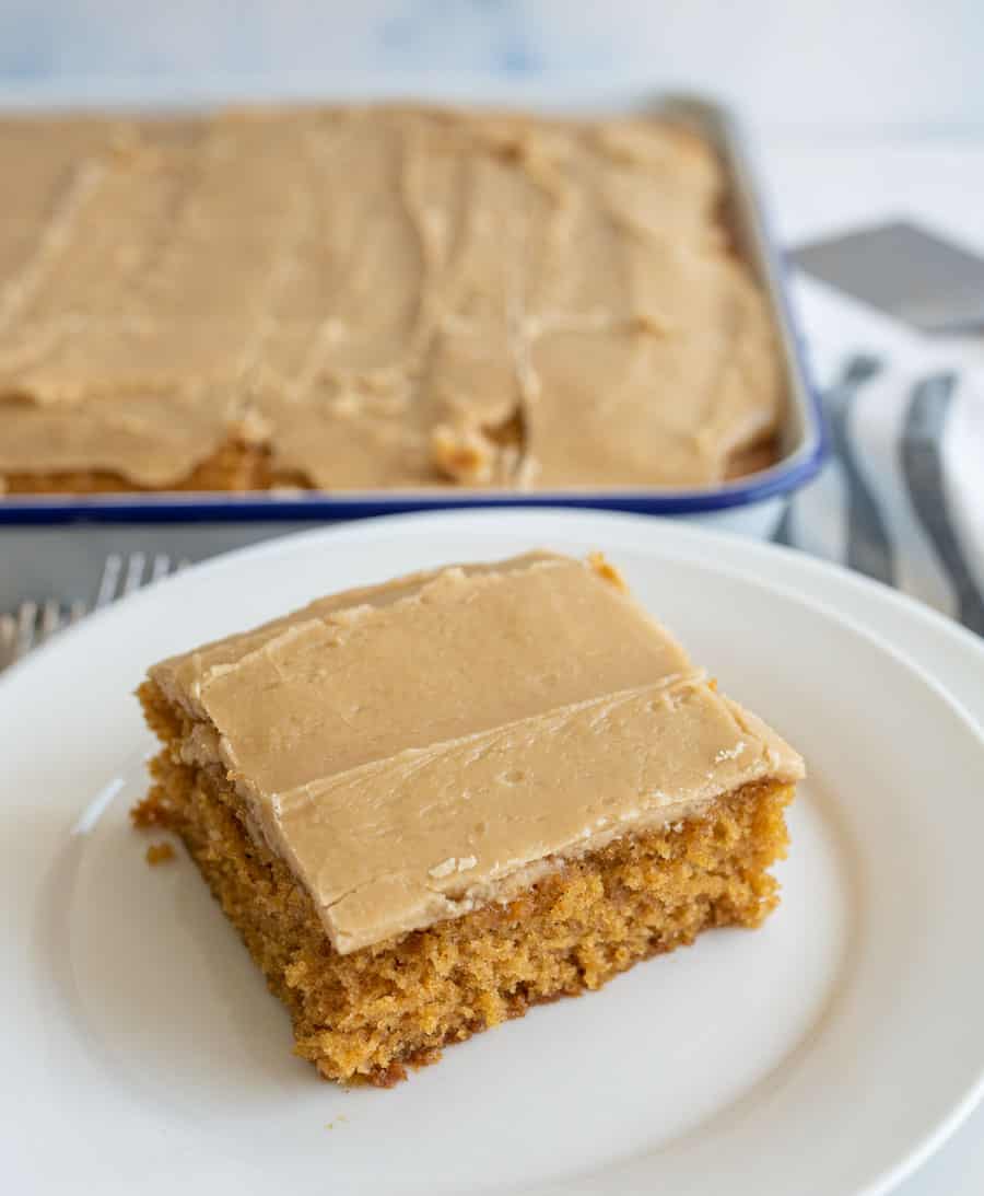 one square of pumpkin cake with caramel icing on a white plate