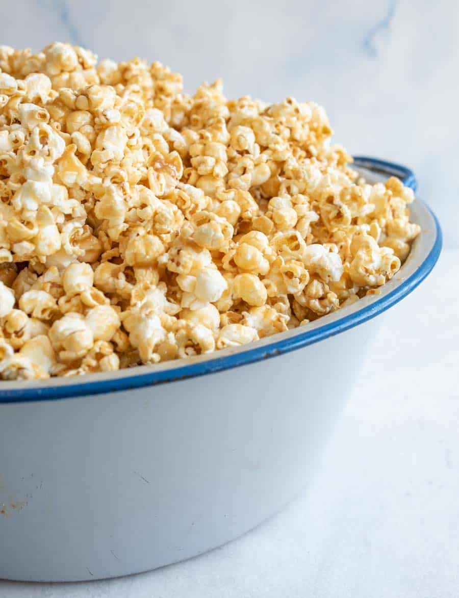 side view of soft caramel popcorn on a big white and blue bowl