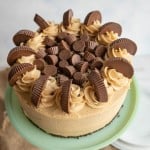 tan peanut butter frosting over a round cake with peanut butter cups on top