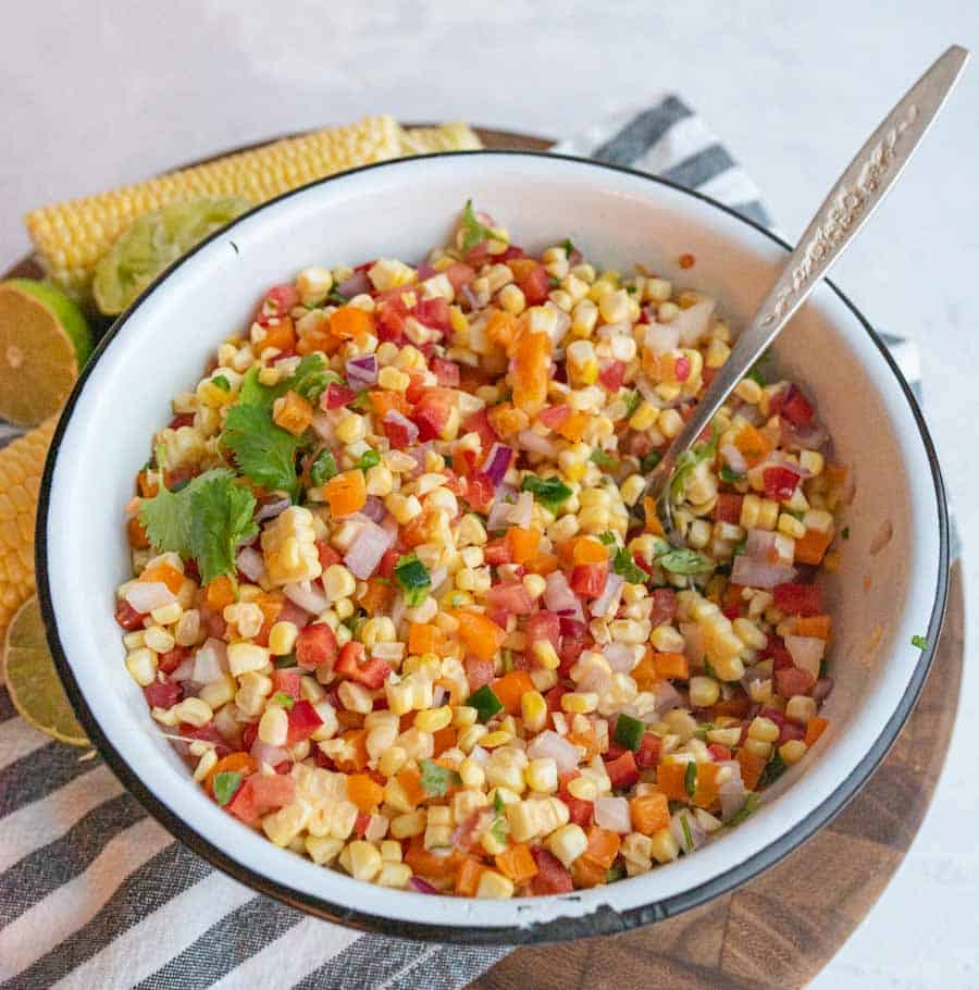 corn salsa in a white bowl with a spoon