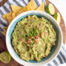 top view of bowl with guacamole and tortilla chips around it