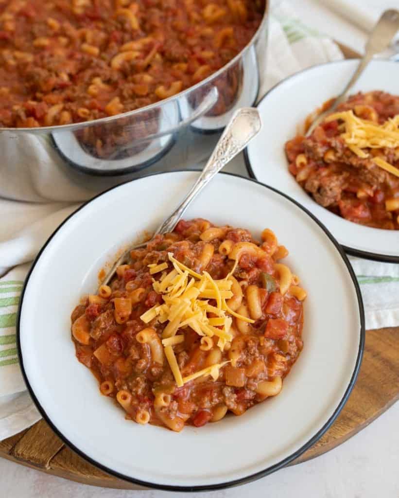 close up of two bowls of goulash with a pot in the background