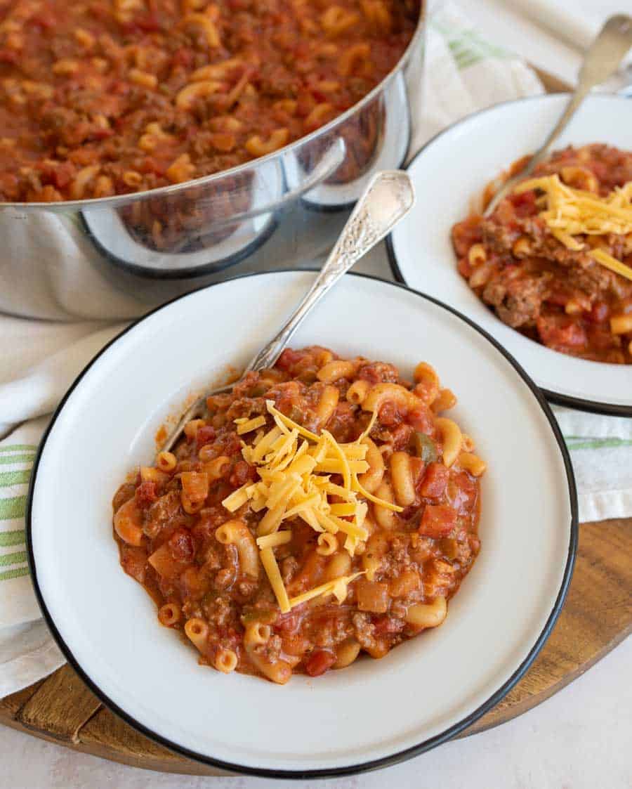 close up of two bowls of goulash with a pot in the background