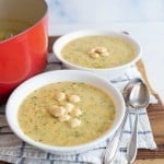 two white bowls and red dutch pot with cheddar broccoli soup and oyster crackers