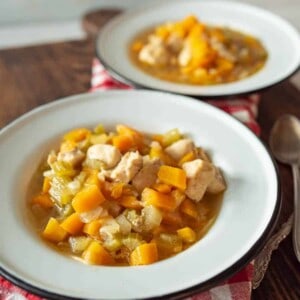 white bowl of chicken soup with hearty vegetables