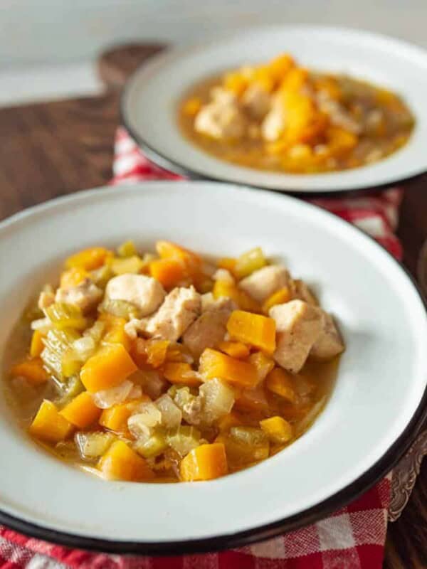 white bowl of chicken soup with hearty vegetables