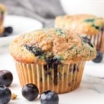 close up perfect image of a blueberry muffin with blueberries around it