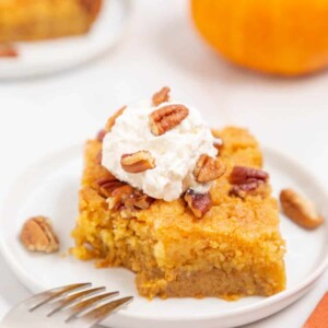 one square slice of a pumpkin dump cake with pecans on top