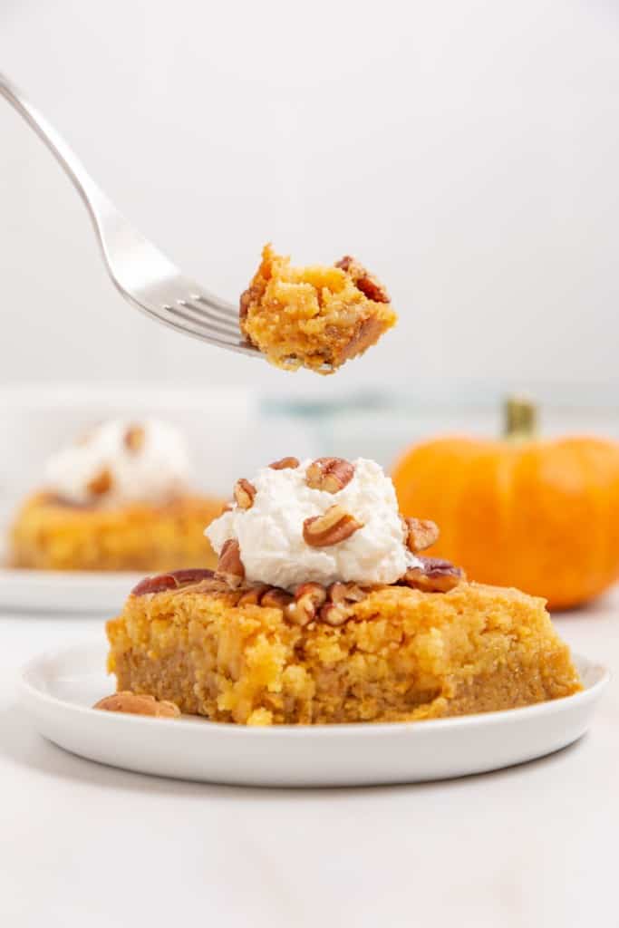 one square slice of a pumpkin dump cake with pecans on top with a fork