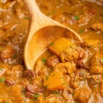 close up in the bowl of pumpkin curry being stirred with a spoon