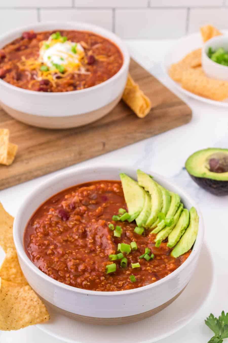 white bowl of vegetarian chili with avocado on top