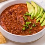 white bowl of vegetarian chili with avocado on top