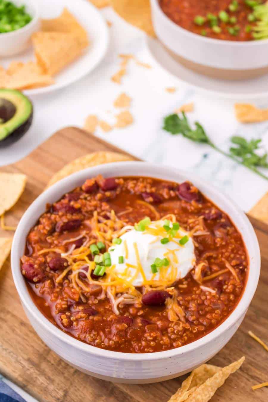 white bowl of vegetarian chili with soup cream and cheese on top