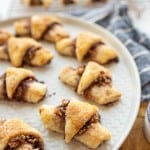 rugelach cookies on a large round plate, which look like stuffed and gooey rustic croissants