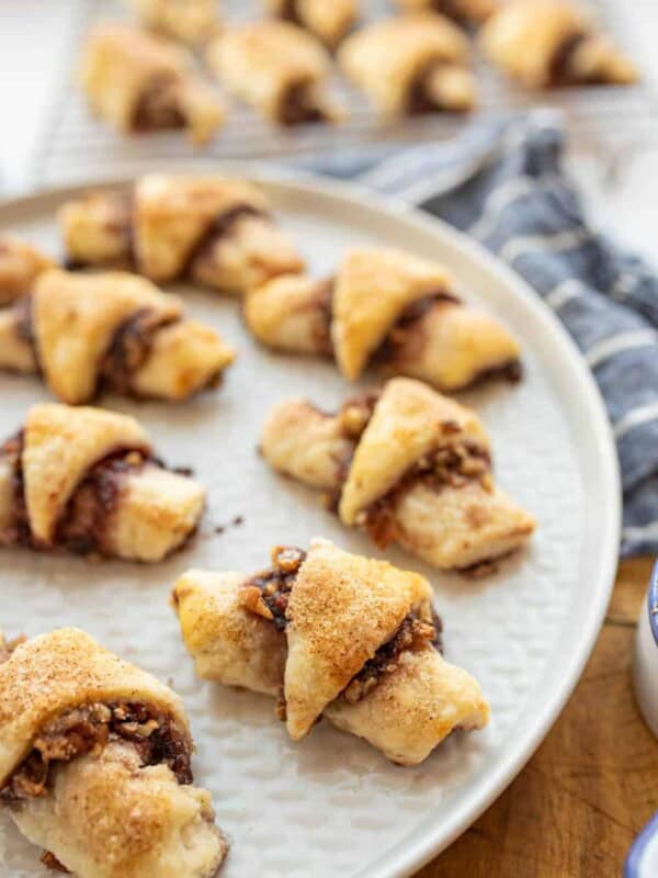 rugelach cookies on a large round plate, which look like stuffed and gooey rustic croissants