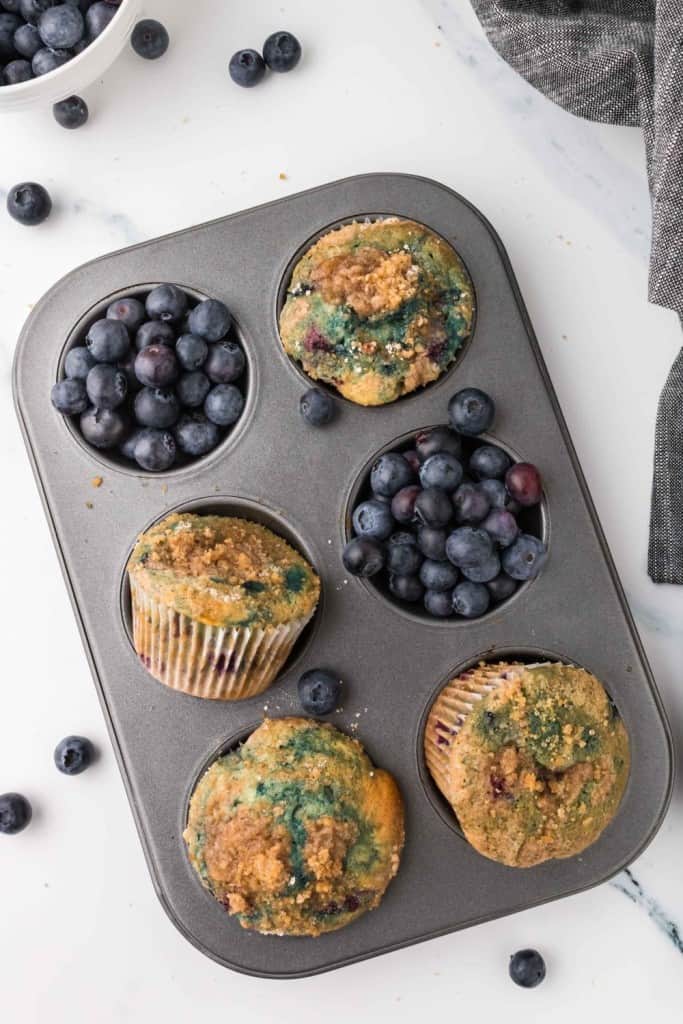 muffin tin with blueberry muffins and fresh blueberries